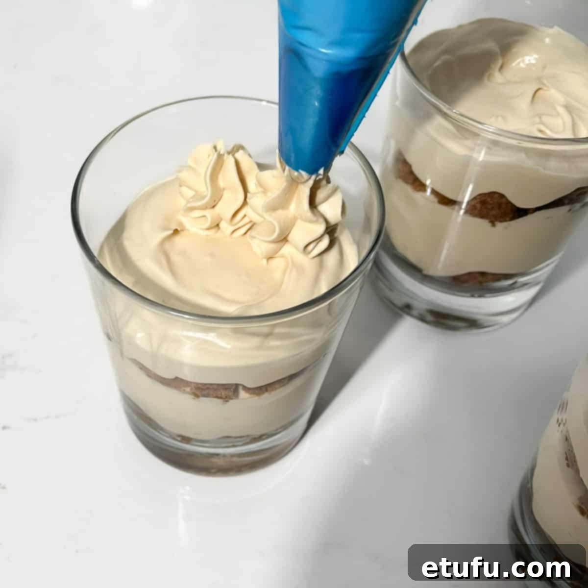 Piping cream onto the speculoos tiramisu.