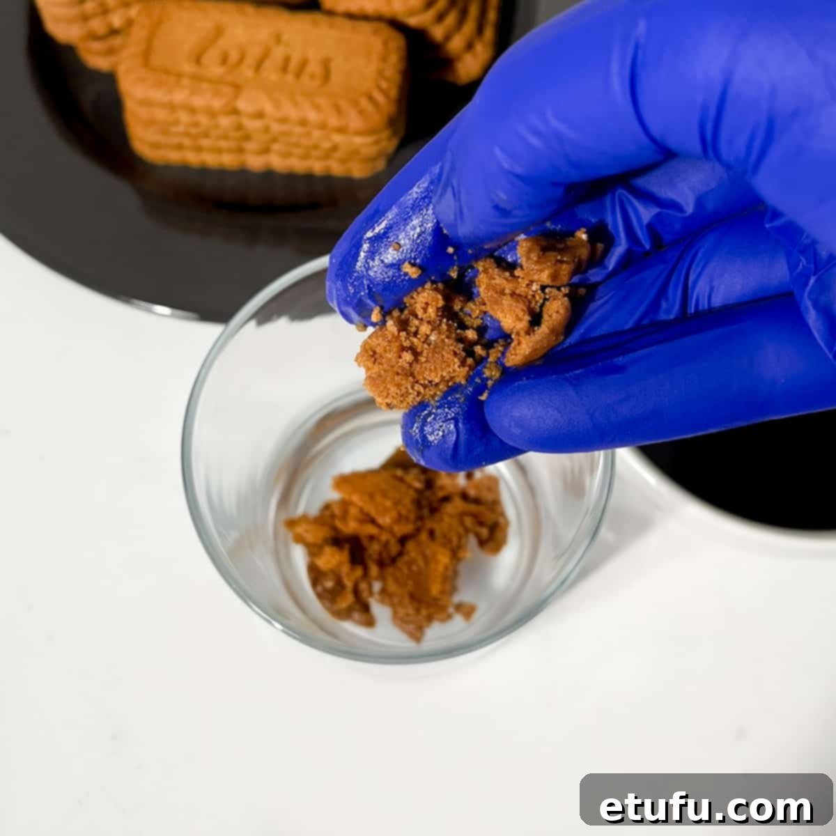 Crumbling biscoff cookies into a glass.