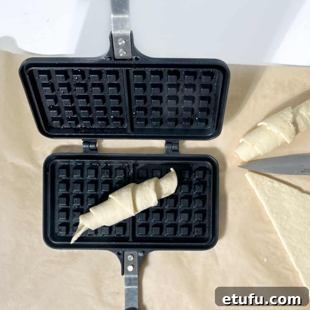 An unbaked, rolled croissant in a waffle pan.