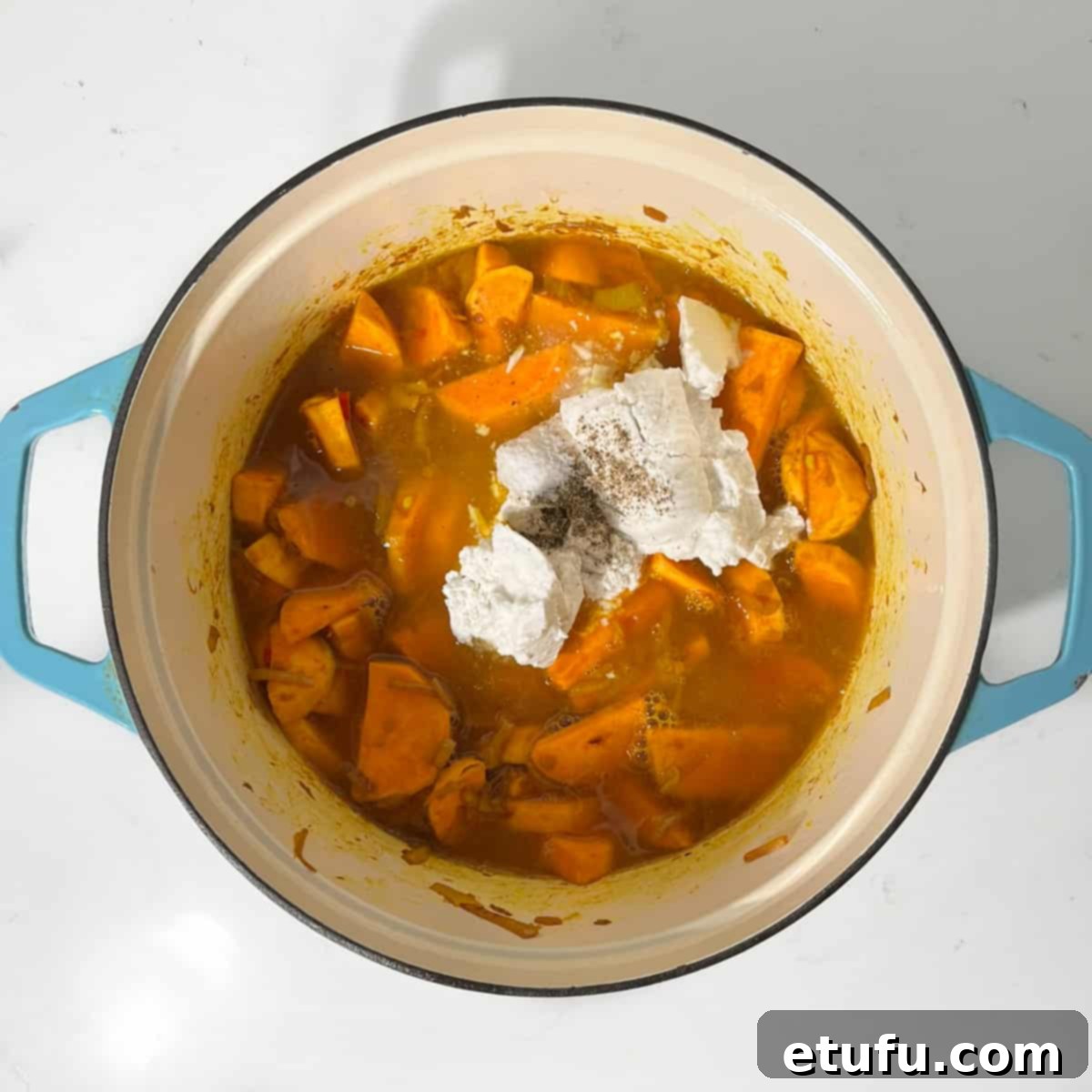 Adding the coconut milk and vegetable stock to the sweet potatoes.