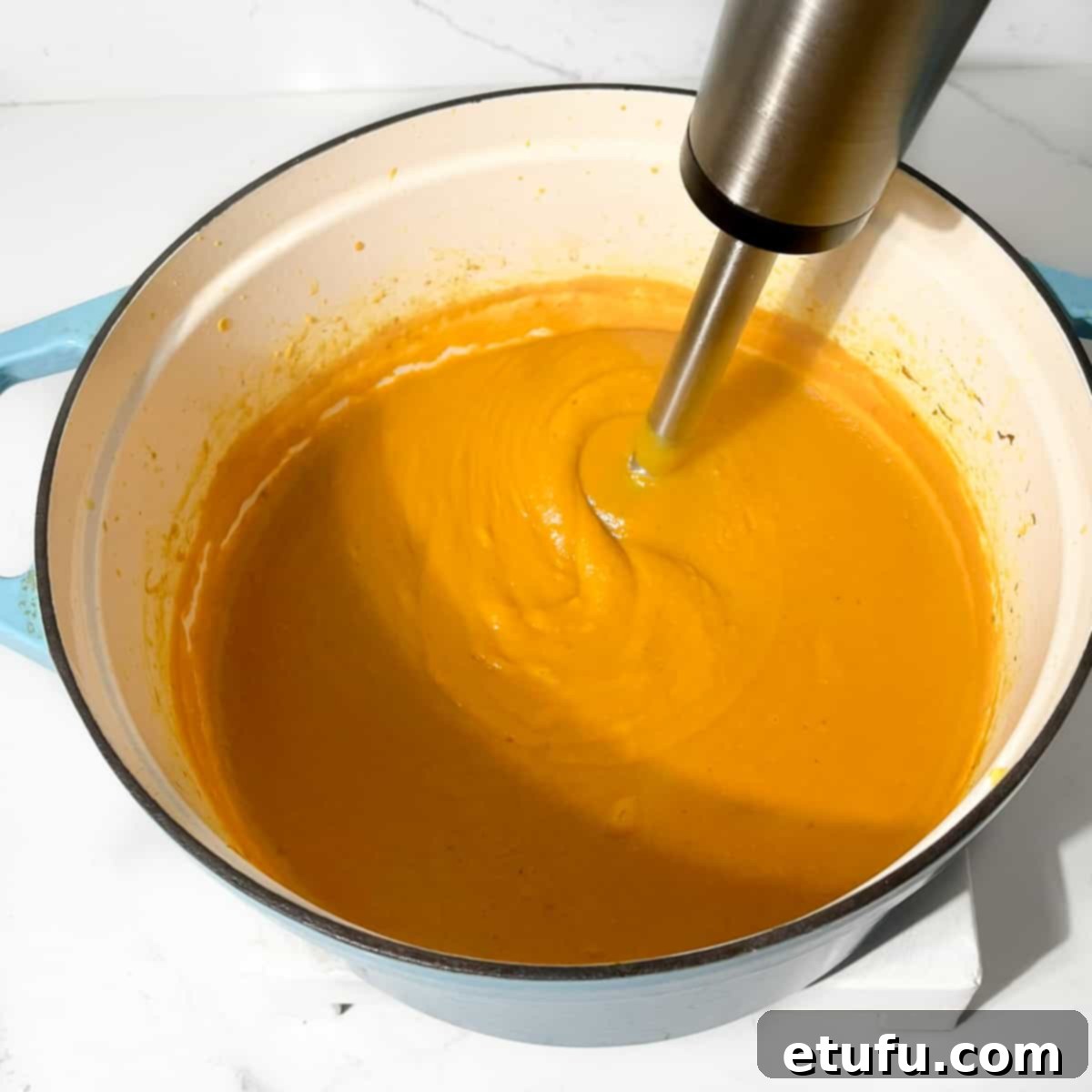 Blending the sweet potato coconut and chilli soup with a stick blender.