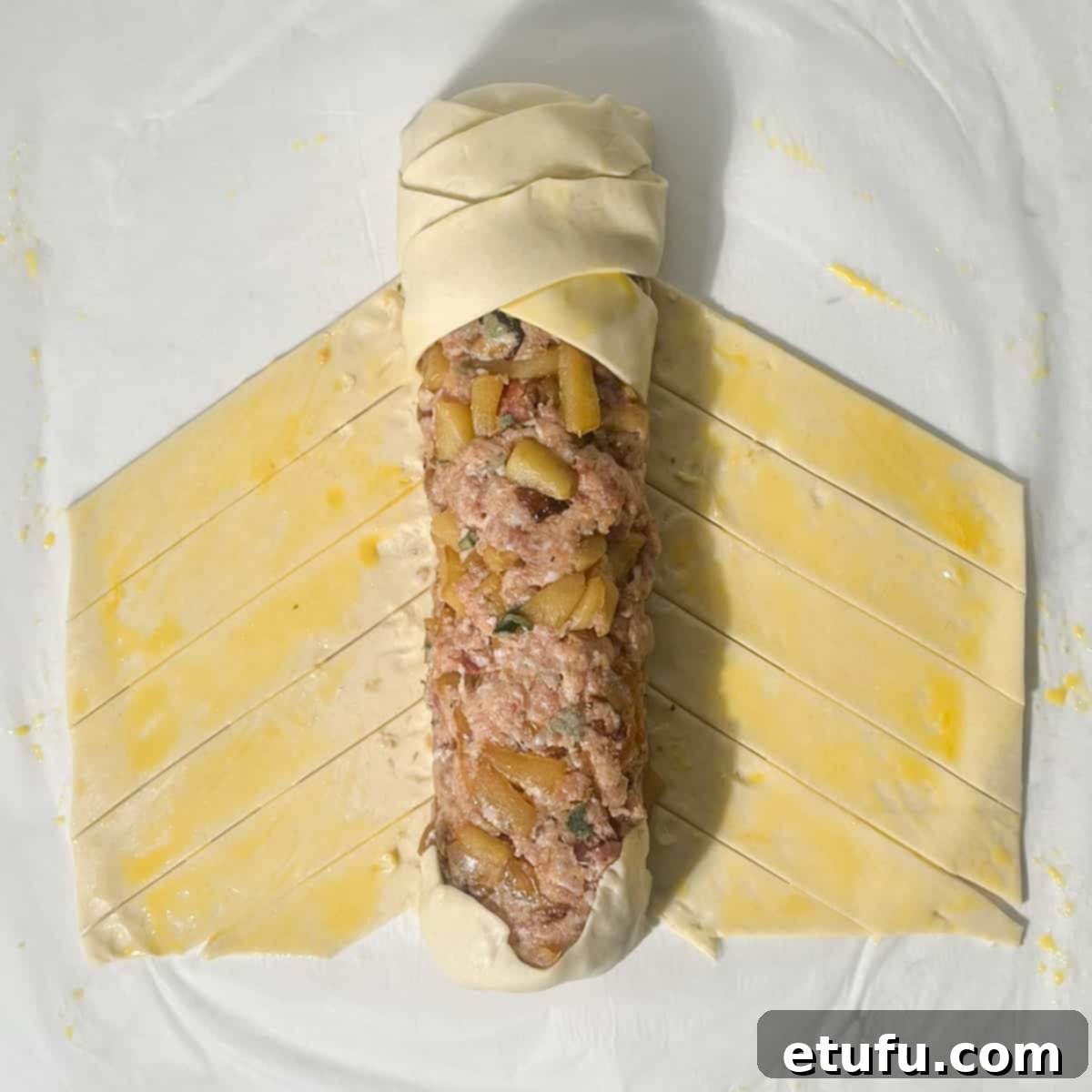 Plaiting the pastry across the sausage meat mixture.