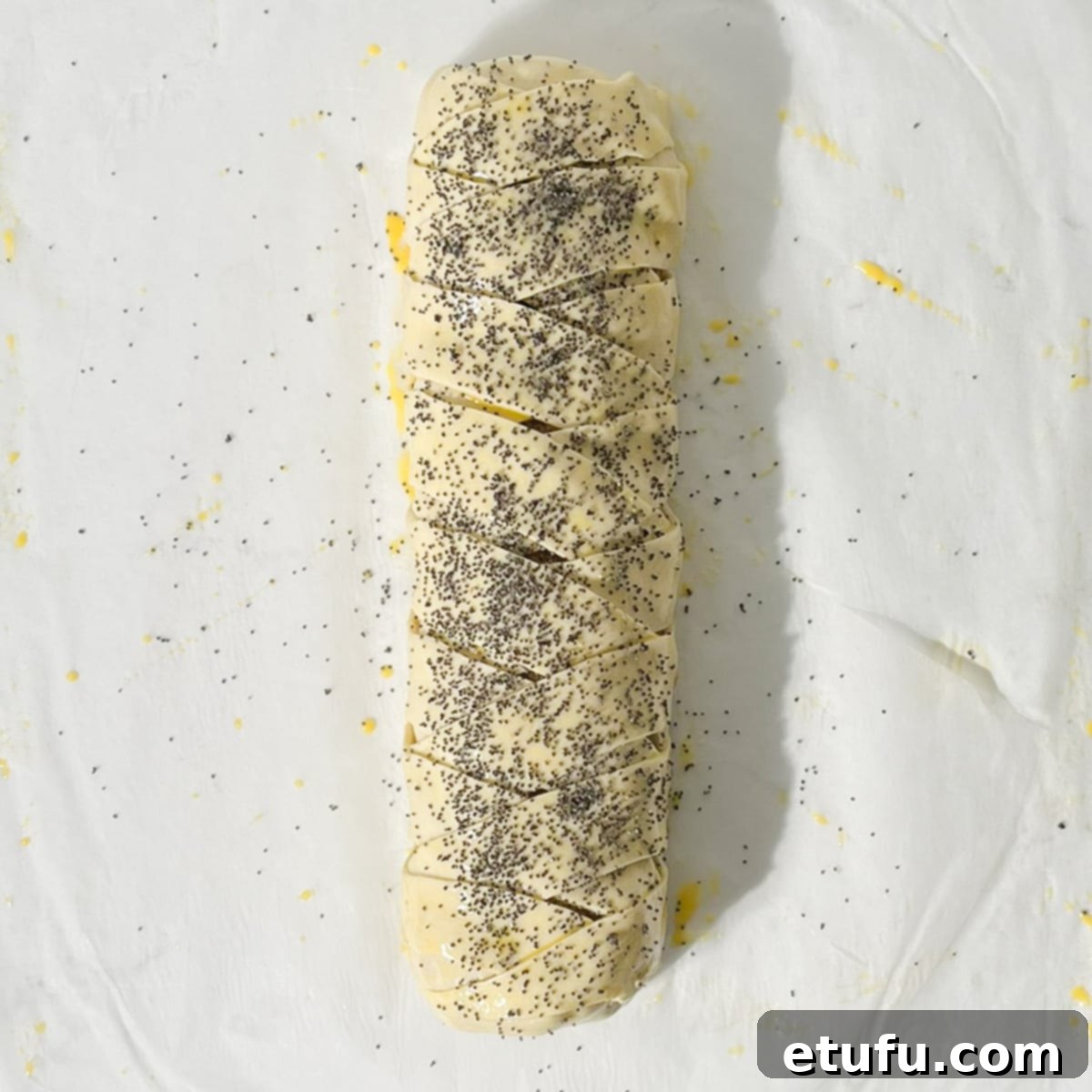 Sprinkling poppy seeds onto the giant sausage roll.