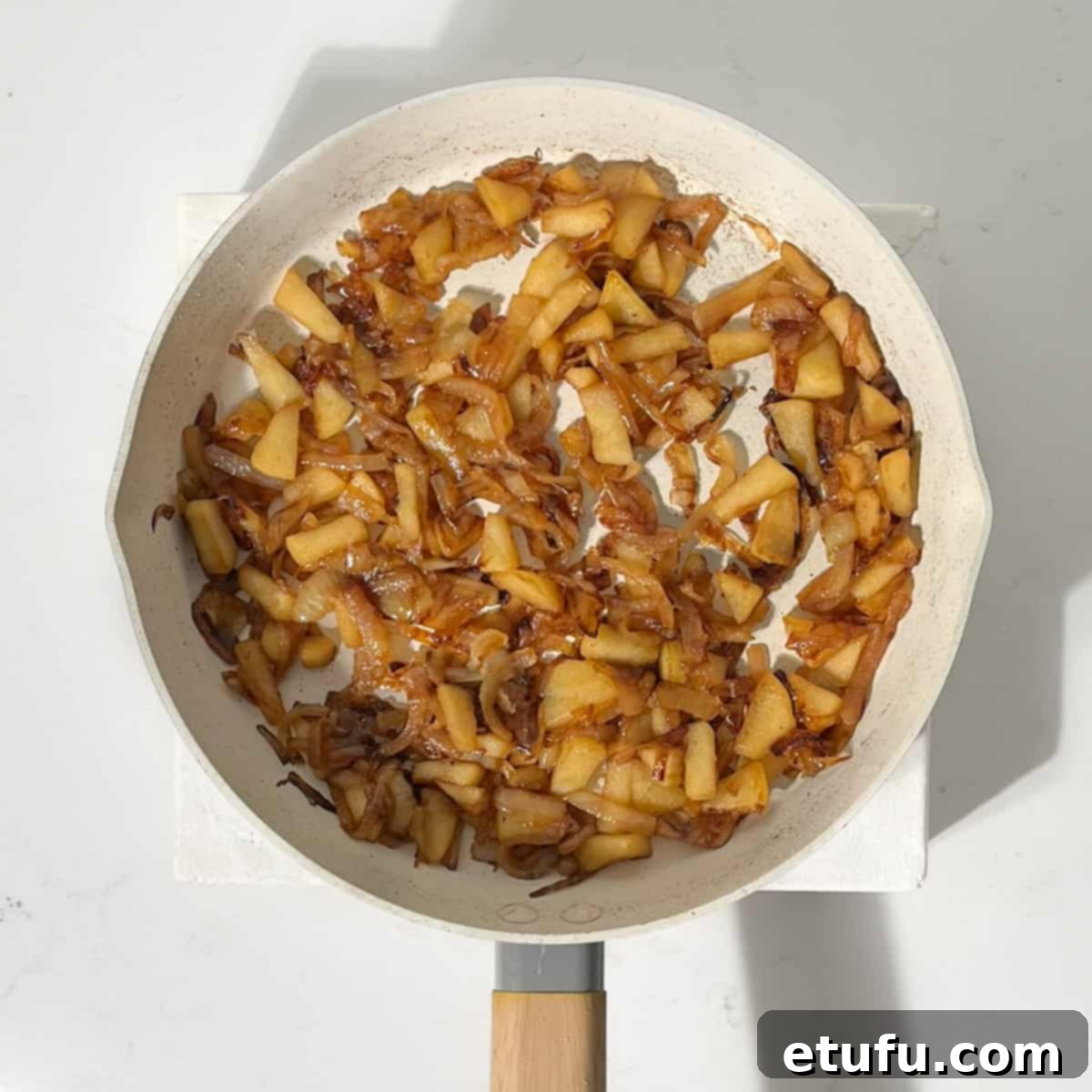 Caramelised apples and onions in a large frying pan.