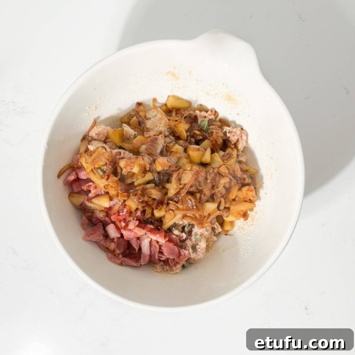 Adding the caramelised onions and apple to the breadcrumb mixture.