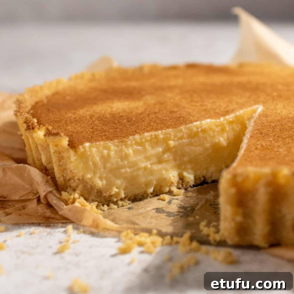 A whole South African milk tart with one slice cut out, revealing its creamy texture.