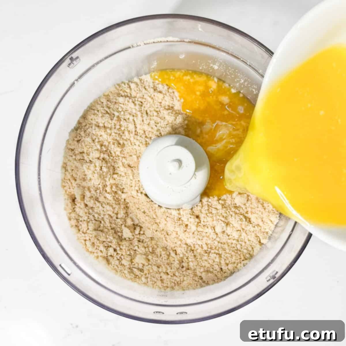 Adding melted butter to crushed biscuit crumbs for the milk tart crust.