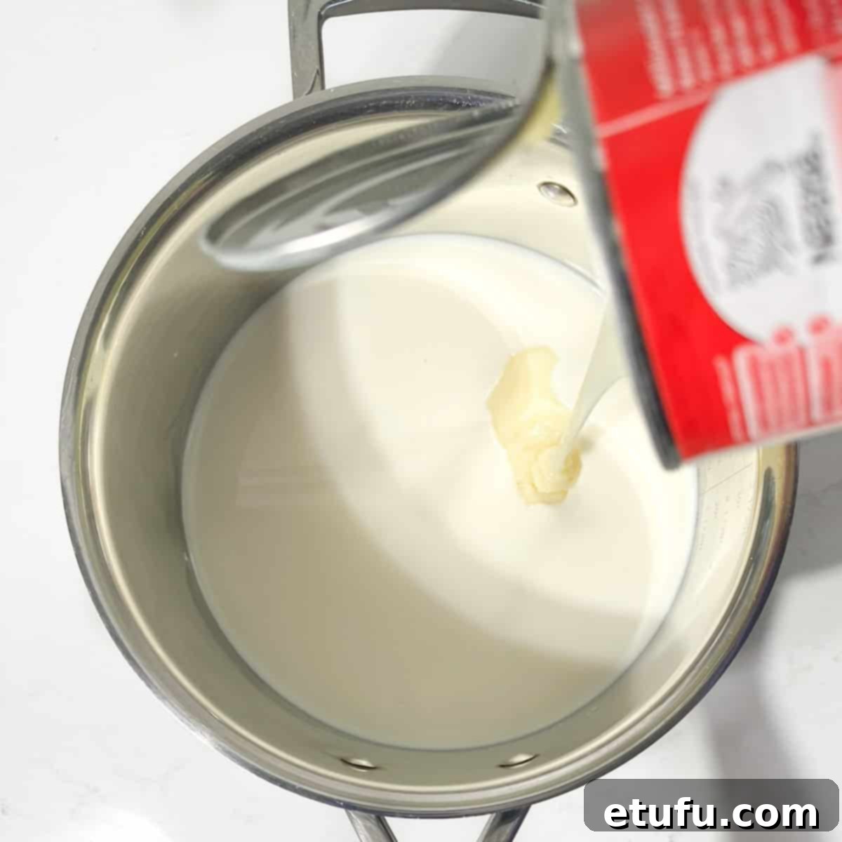 Adding condensed milk to full cream milk in a large saucepan.