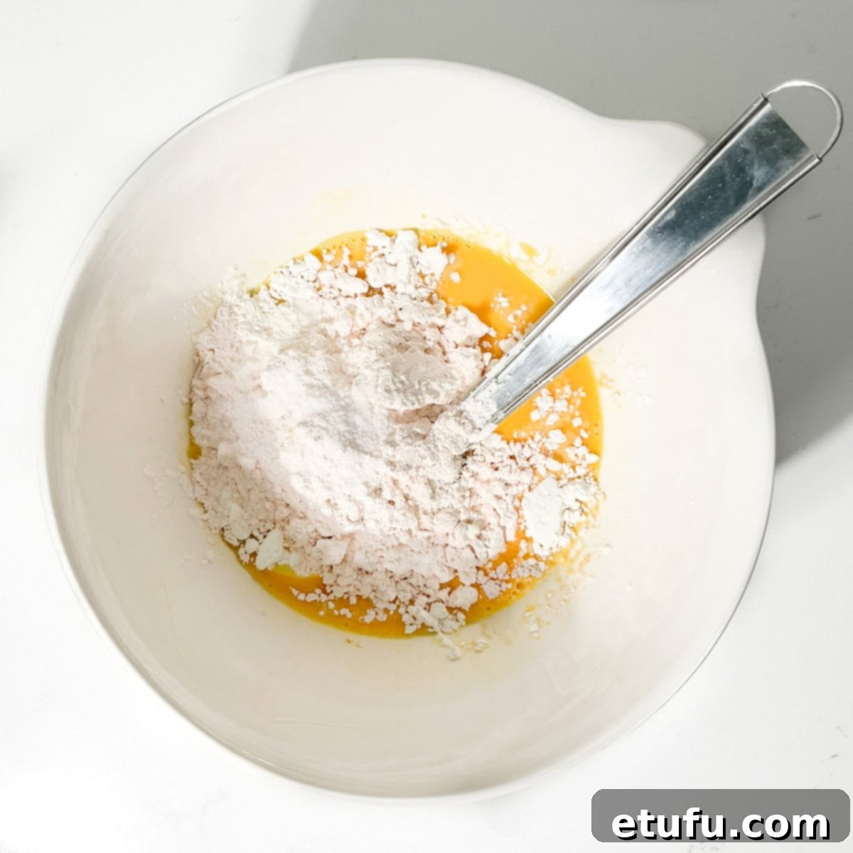Adding cornflour and custard powder to the egg yolk mixture.