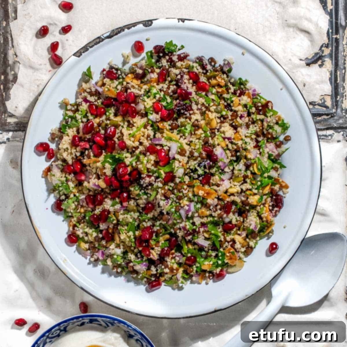 Cypriot grain salad on old white metal tiles with a bowl of Greek yoghurt dressing.