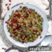 Cypriot grain salad on old white metal tiles with a bowl of Greek yoghurt dressing.