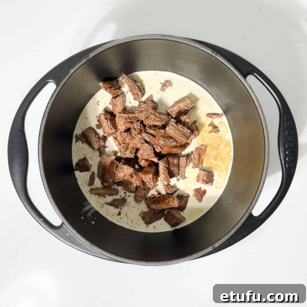 Adding sliced Bar-one bars to cream in a small saucepan for the Bar-one sauce.