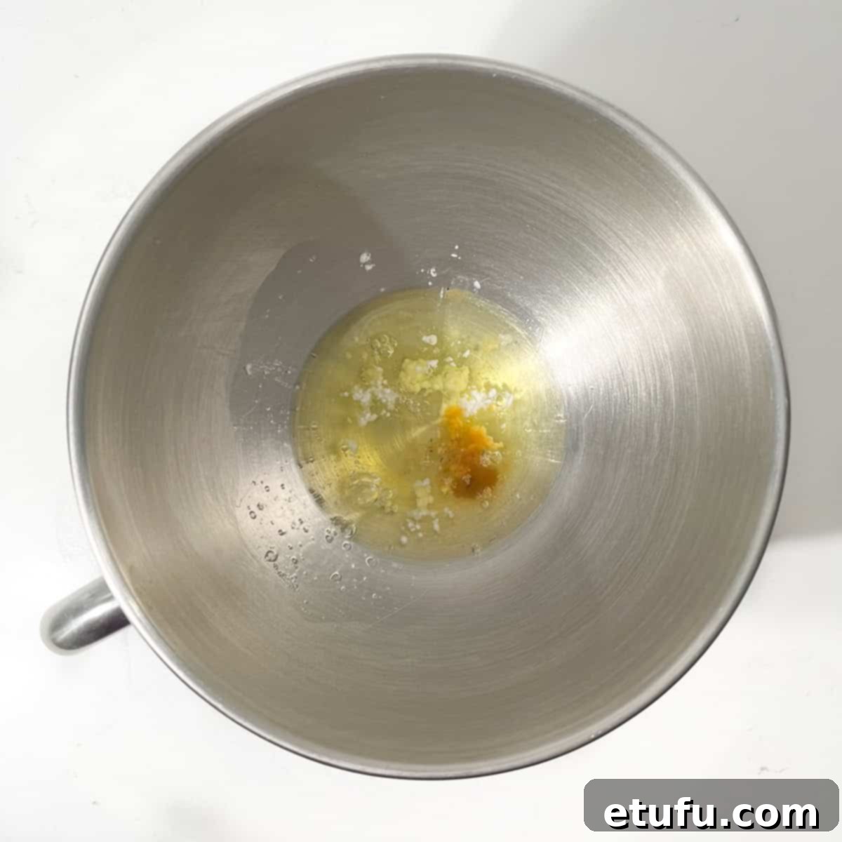 Egg whites being poured into the clean, grease-free bowl of a stand mixer, ready for whipping into meringue.