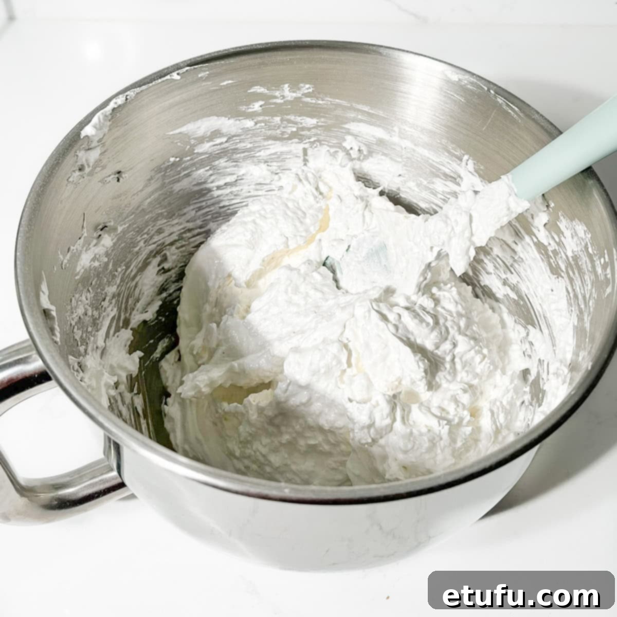 The meringue coconut topping after gentle folding, showing the incorporated coconut flakes within the fluffy mixture.
