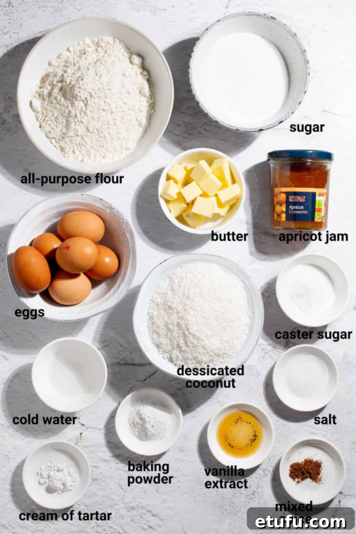 Various ingredients laid out for making Hertzoggies, including flour, butter, eggs, and coconut.