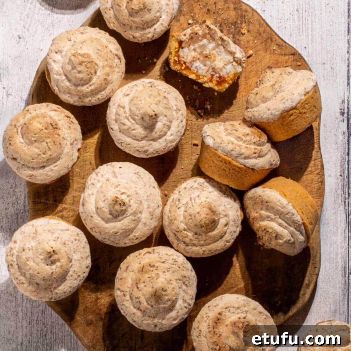 Freshly baked Hertzoggies arranged on a wooden board against a white background, highlighting their golden, toasted meringue and perfectly baked pastry.