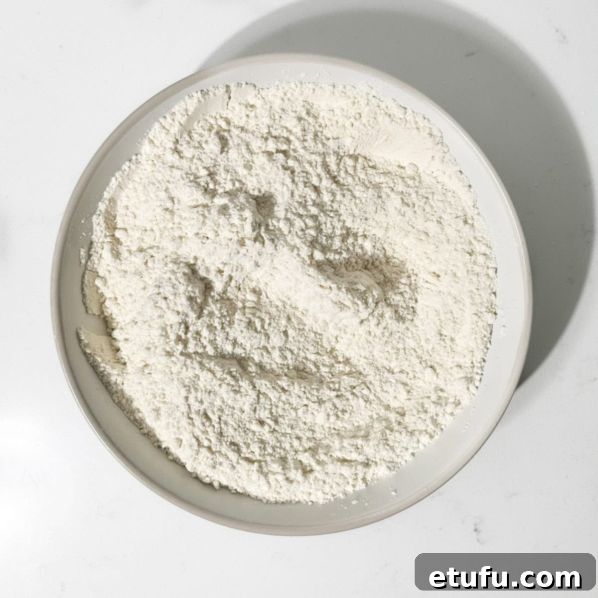 Dry ingredients for Hertzoggies, including flour, sugar, baking powder, mixed spice, and salt, in a white bowl.