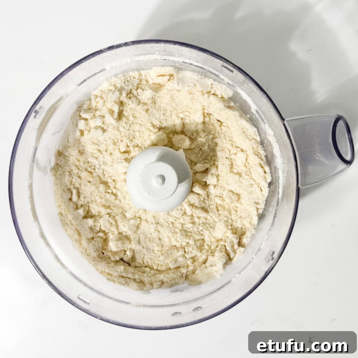 The pastry dough for Hertzoggies after processing, showing a crumbly, breadcrumb-like texture in the food processor.