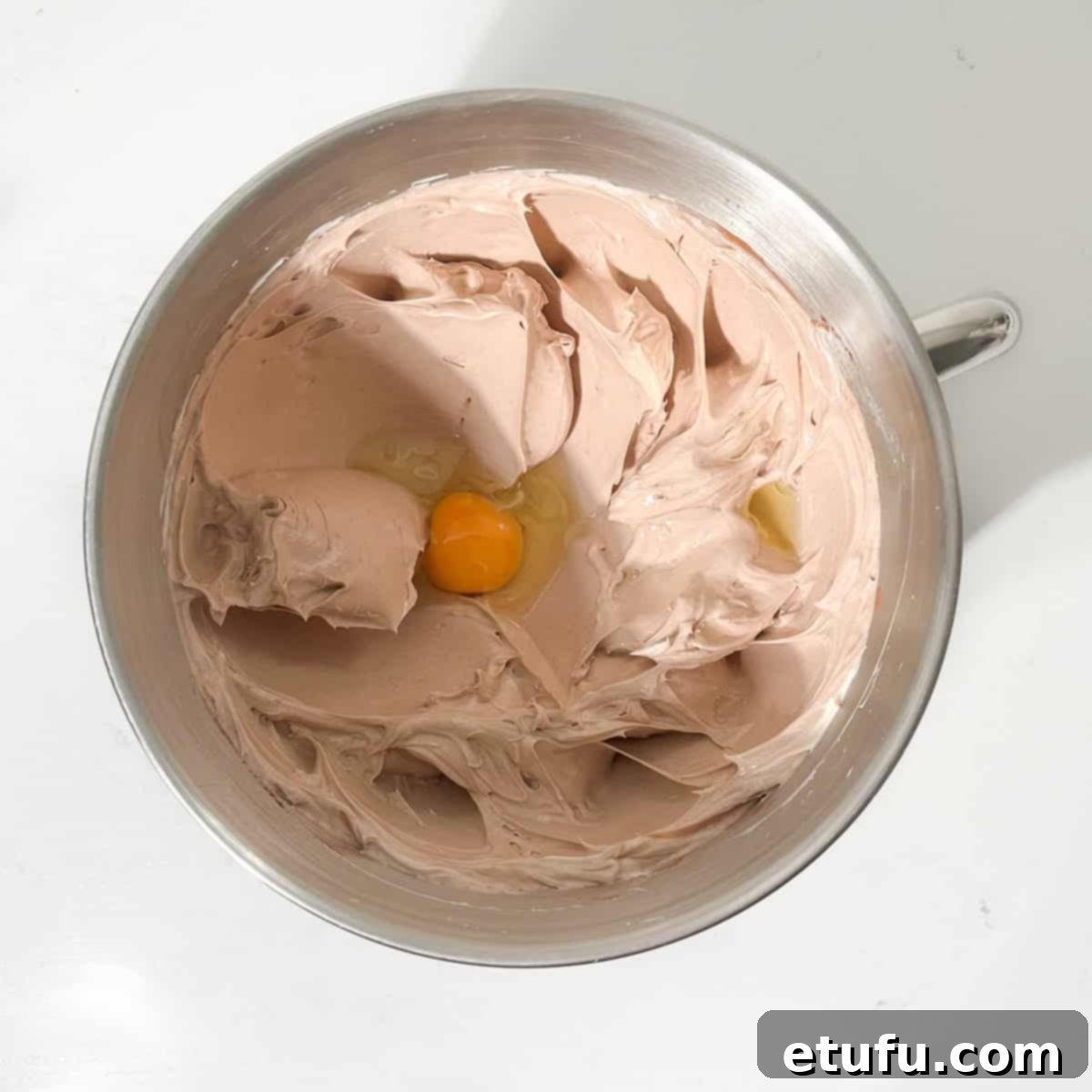 Adding one egg to the chocolate cake mixture.