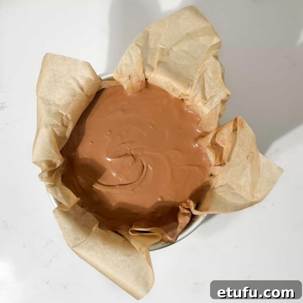A baked chocolate cheesecake in a baking tin, ready to go into the oven.
