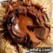 A chocolate basque cheesecake in the baking paper it was baked in with two slices cut from it.