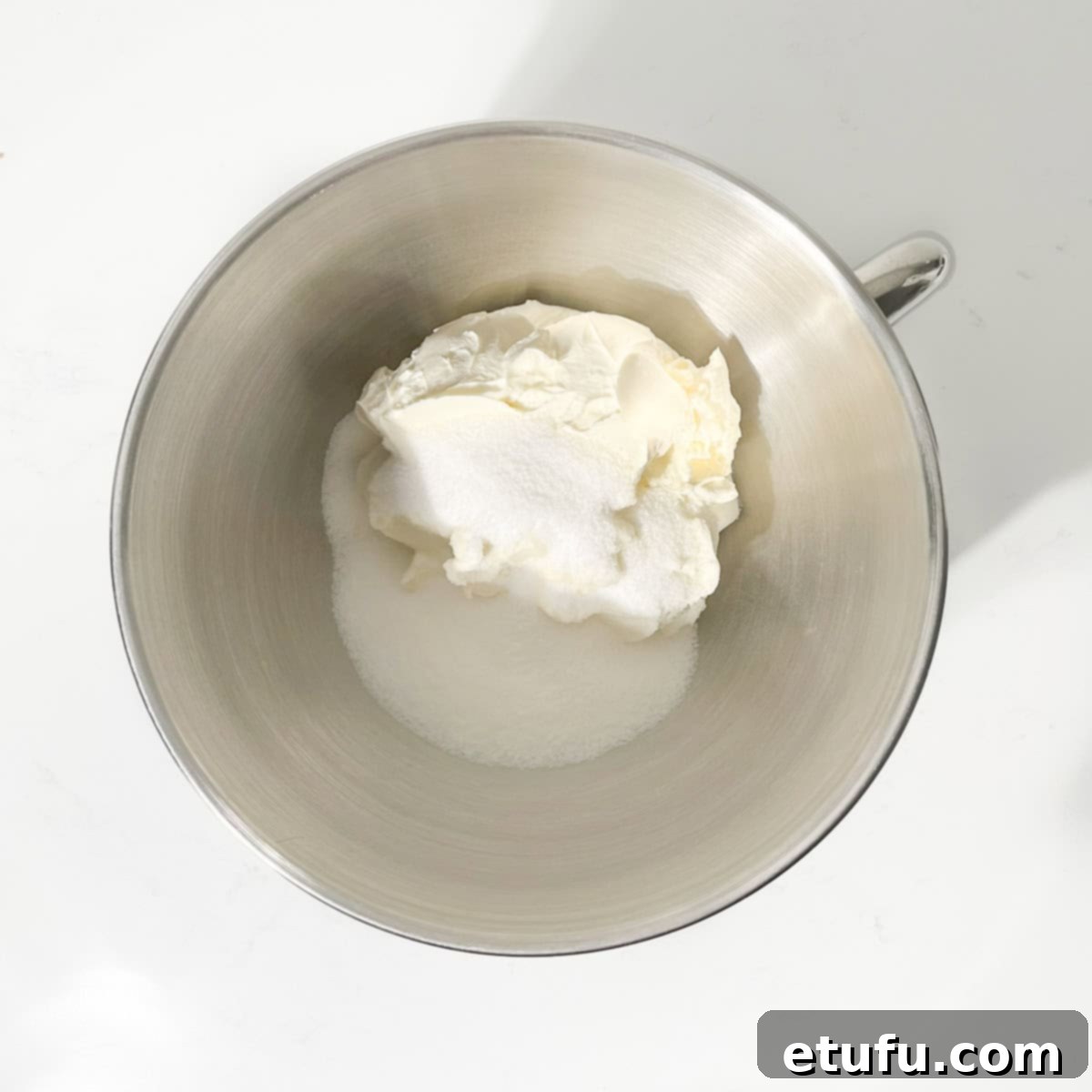 Cream cheese and sugar in the bowl of a stand mixer.