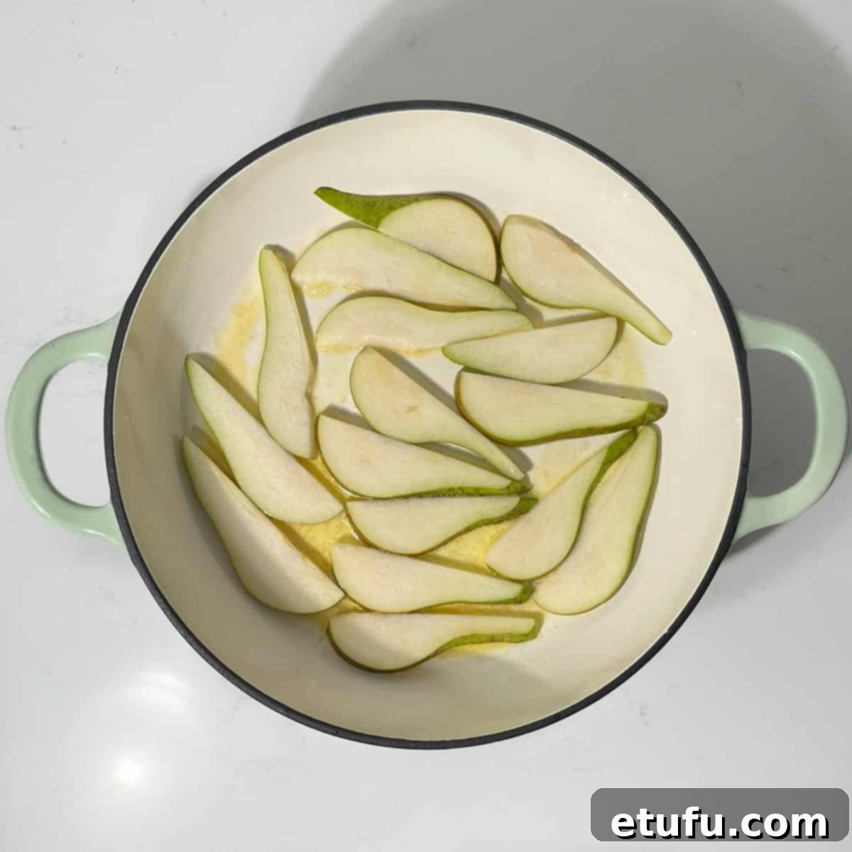 Adding pear slices in a single layer to the hot butter and honey in the frying pan.