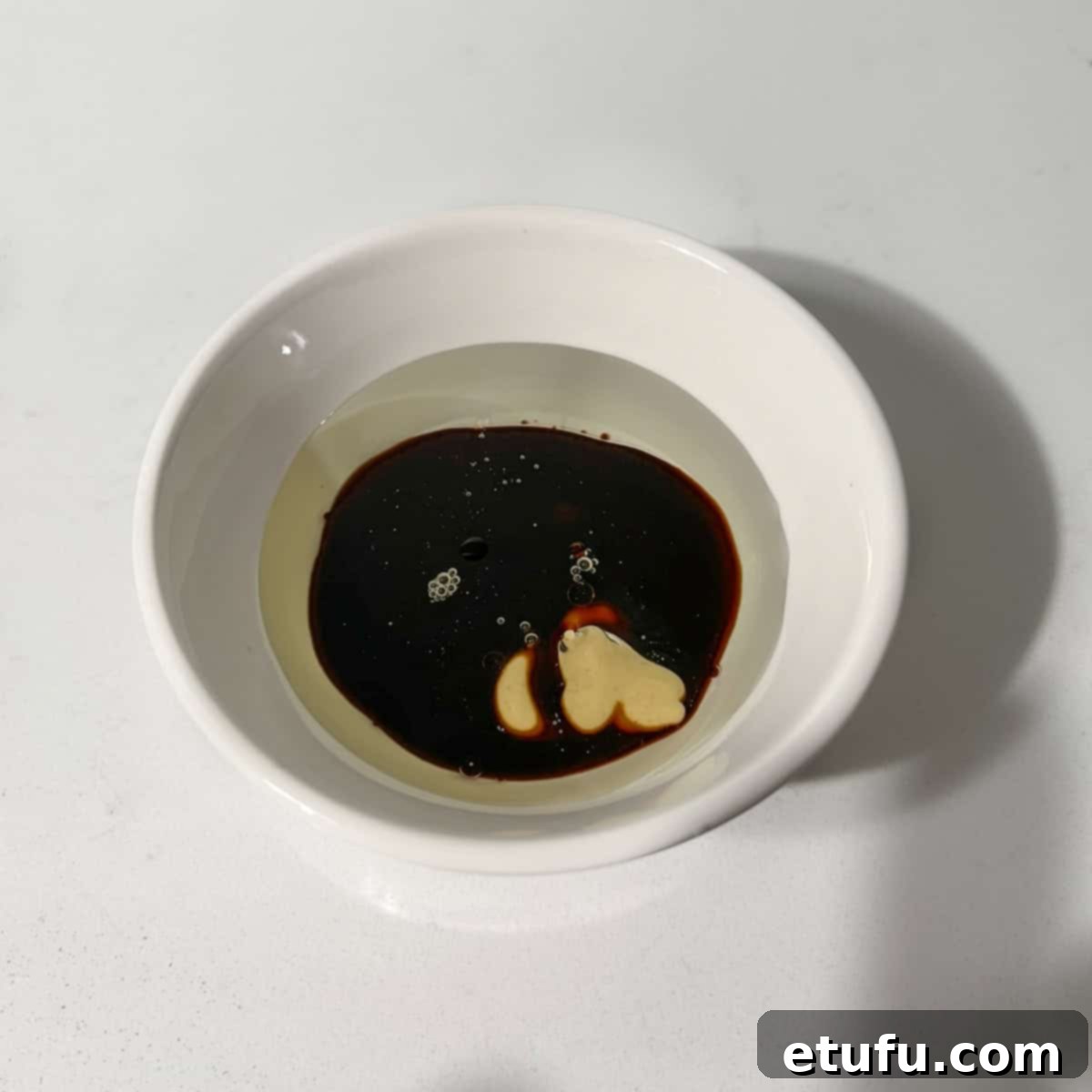 Whisking together ingredients for the honey-balsamic dressing in a small bowl.