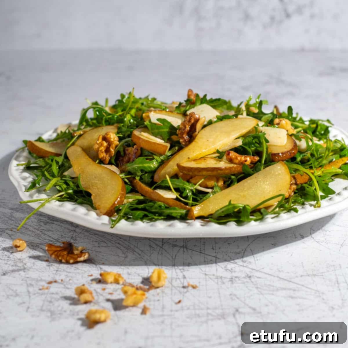 Pear and rocket salad served beautifully on a large white plate, ready to enjoy.
