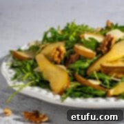 Pear and rocket salad on a large white plate, ready to be served.