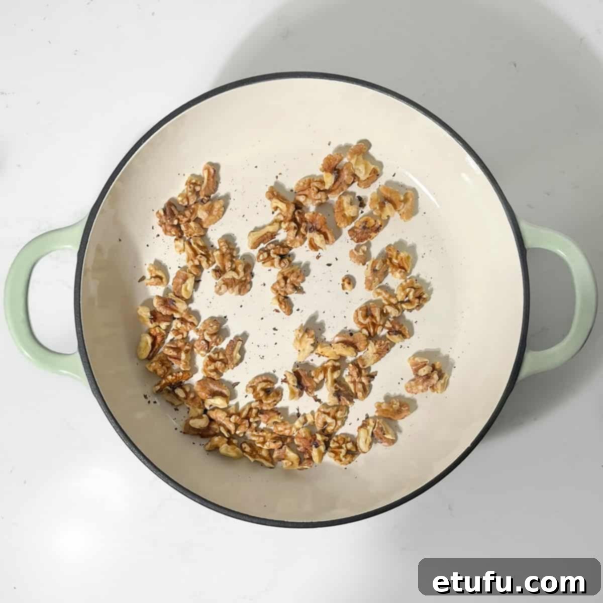 Toasting walnuts in a large frying pan until fragrant and golden.