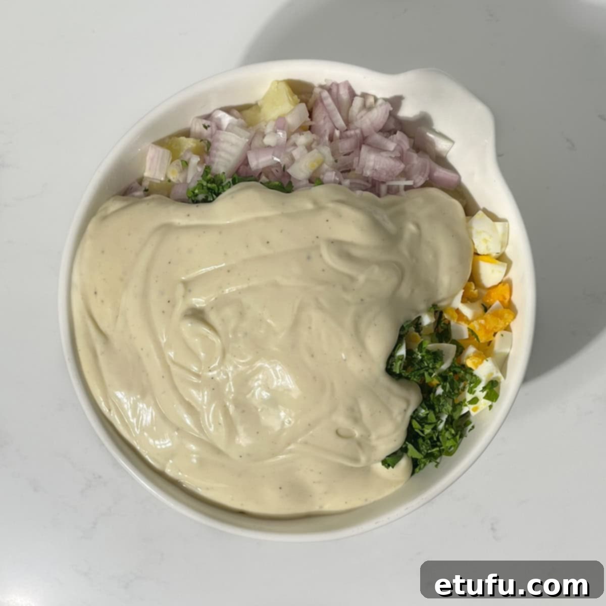 Adding the condensed milk dressing to the South African potato salad.