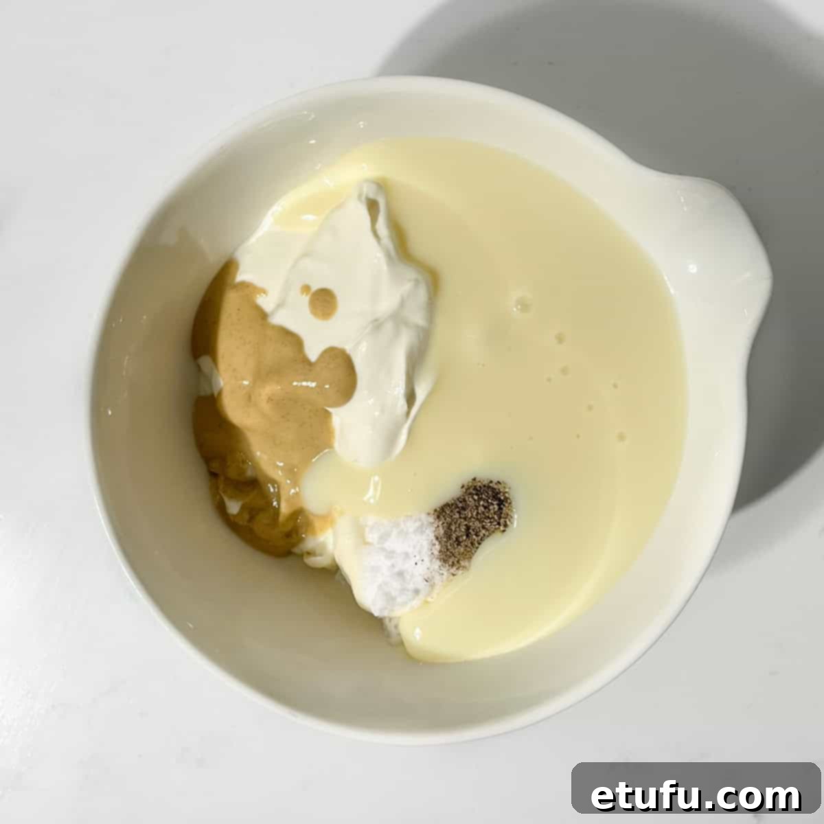 Adding the condensed milk dressing ingredients to a small white bowl.