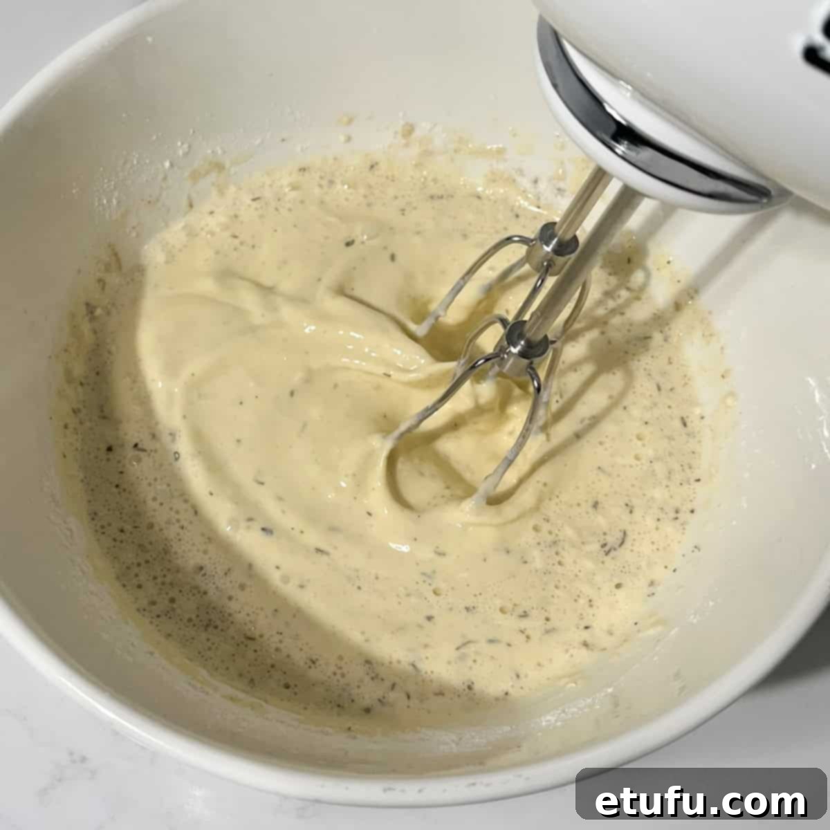 Beating the flour and seasonings into the egg and milk mixture until smooth.