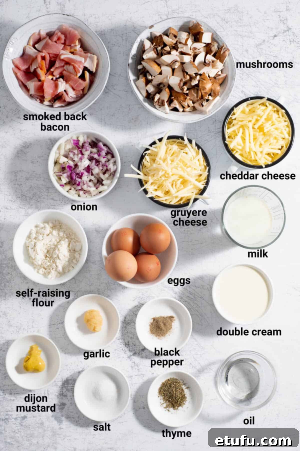 Arrangement of fresh bacon, mushrooms, onions, eggs, milk, cream, and various seasonings for quiche preparation.