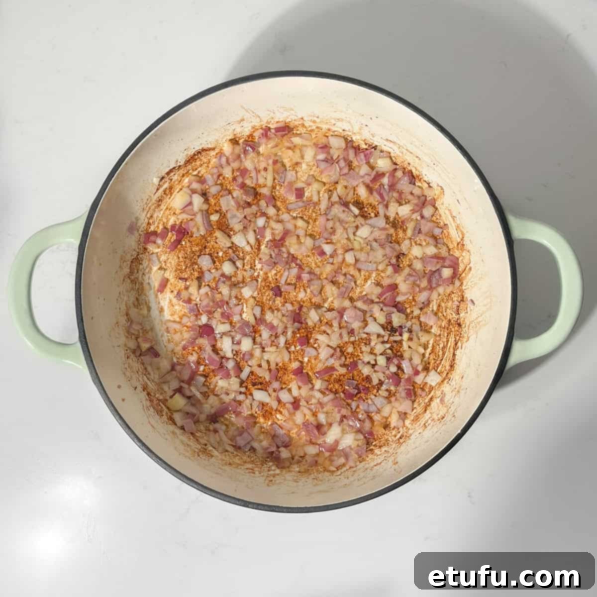 Finely chopped onions sautéing gently in a frying pan, becoming soft and translucent.