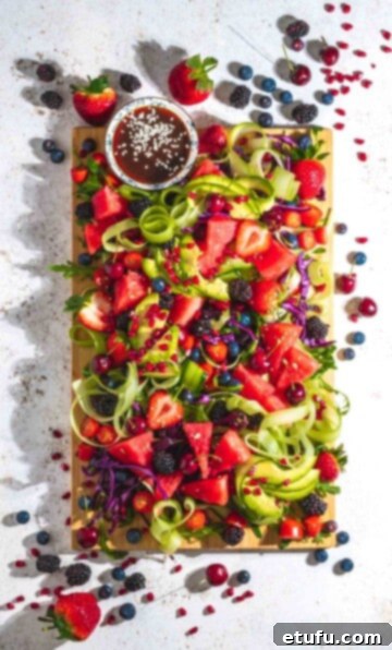 Vibrant rainbow salad displayed on a wooden board against a clean white background.