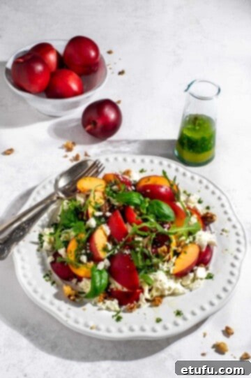 Nectarine salad with rocket and basil dressing on a large white plate.