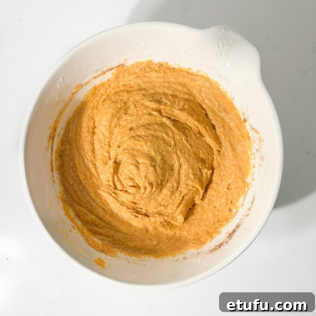 The thick and scoopable pumpkin fritter (pampoenkoekies) batter resting in a large white mixing bowl, ready for frying.
