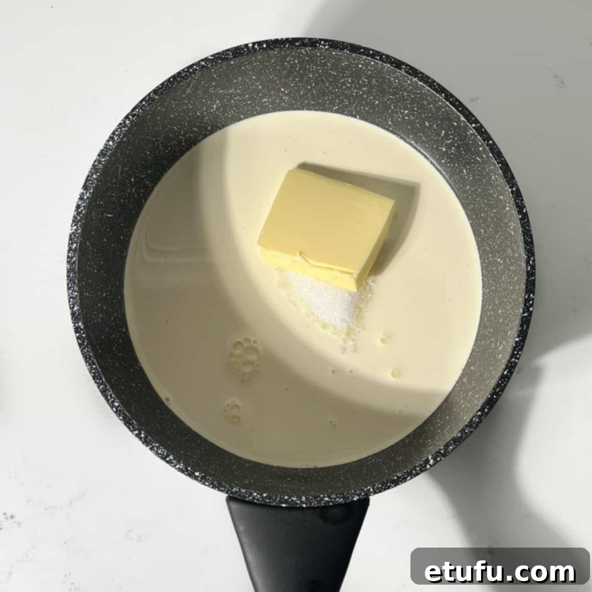 White sugar, heavy cream, milk, and butter are added to a small saucepan, ready to be heated and transformed into a delicious caramel sauce.