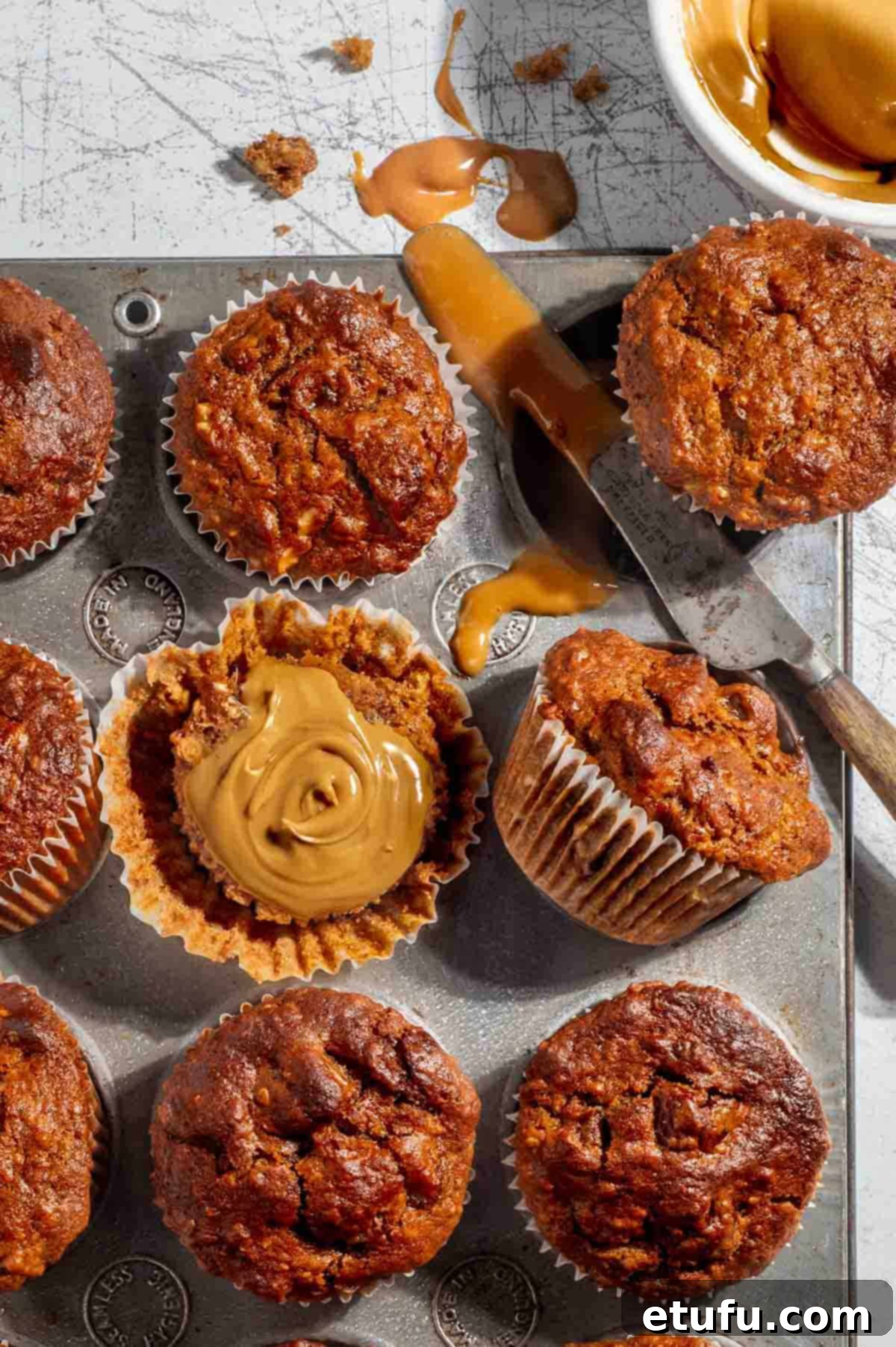 Date muffins in a muffin baking tray with caramel spread, ready to be enjoyed.