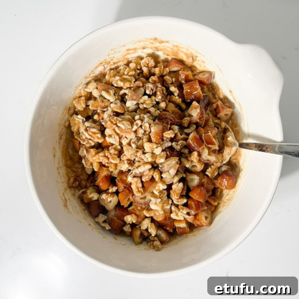Adding drained dates and chopped walnuts to the muffin batter.