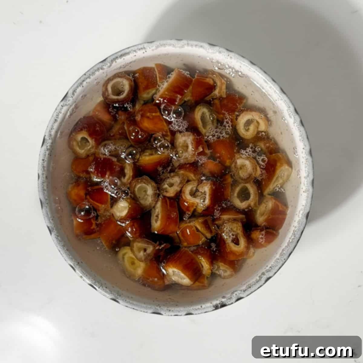 Chopped dates soaking in a bowl of boiled water with bicarbonate of soda.
