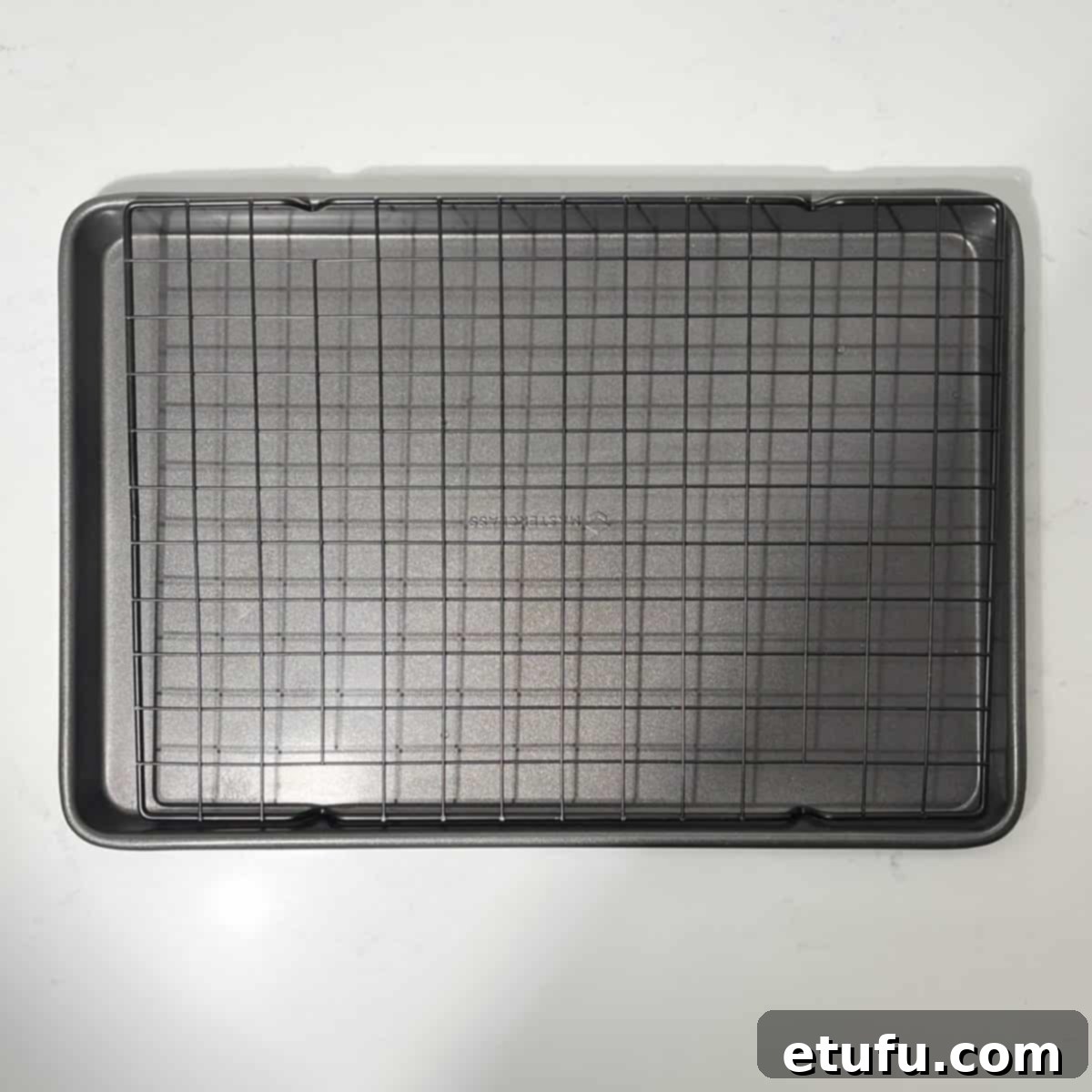 A sturdy wire rack placed inside a rectangular baking tray, ready for cooking.