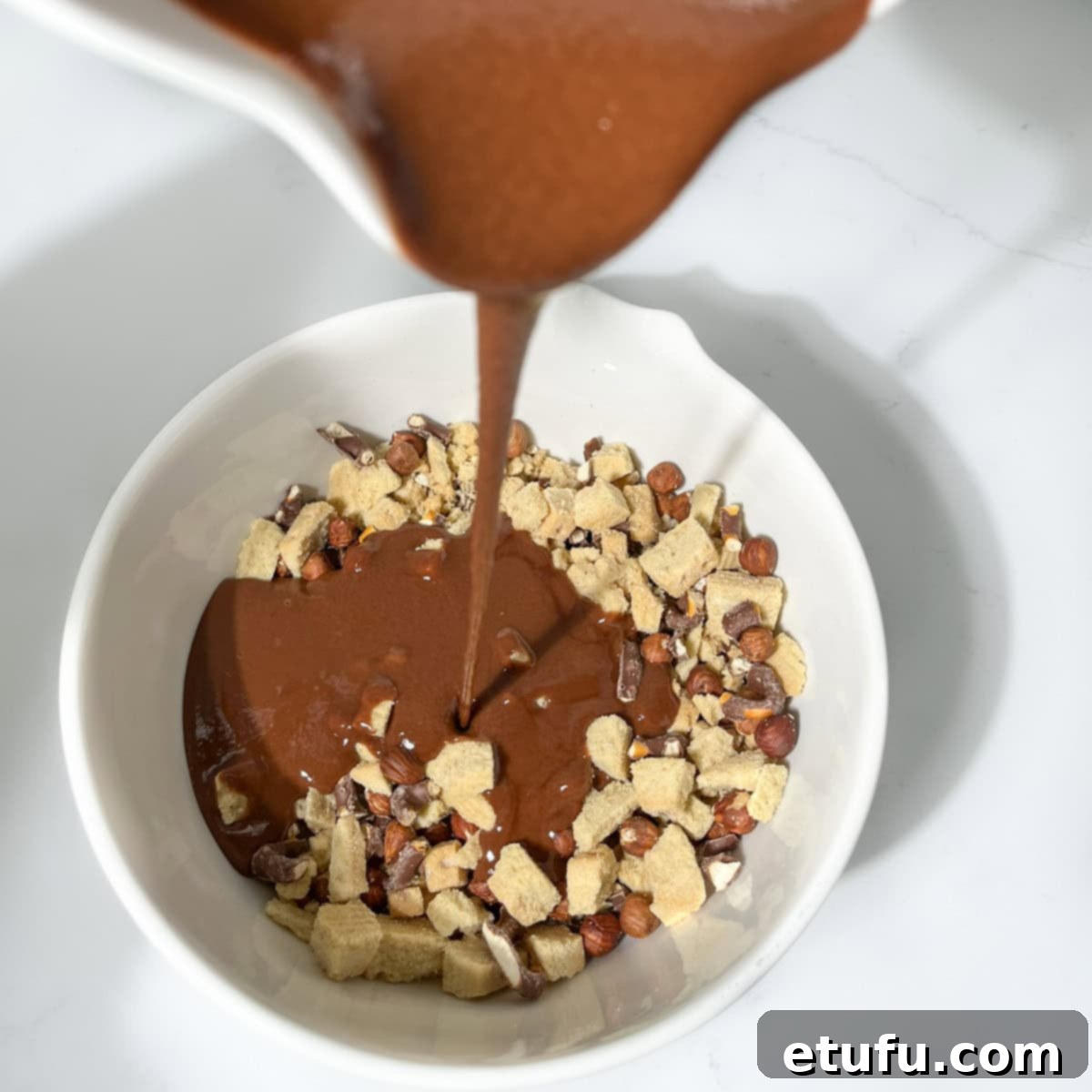 Decadent No-Bake Chocolate Biscuit Delight 8 Pouring the slightly cooled liquid chocolate mixture over the chopped biscuits, nuts, and pretzels.