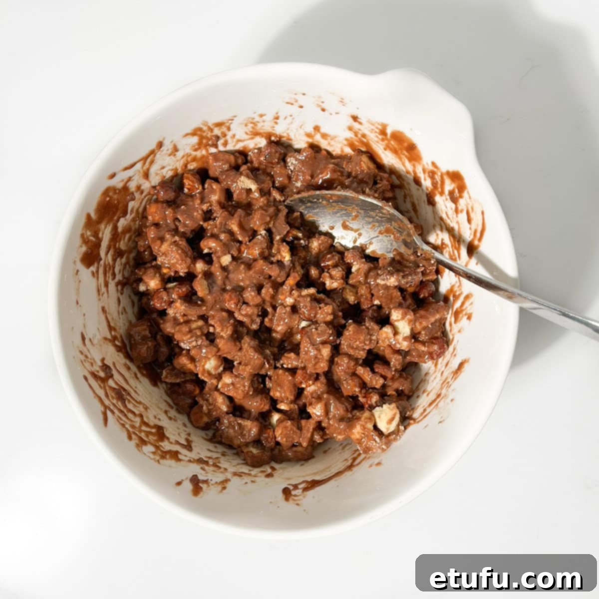 Decadent No-Bake Chocolate Biscuit Delight 9 Mixing the ingredients for the chocolate biscuit cake in a large white bowl to ensure even coating.